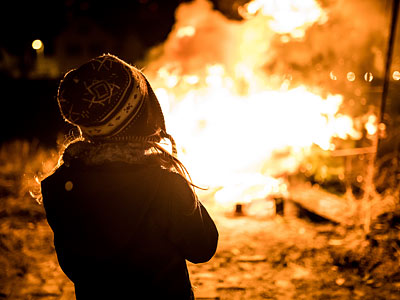 Ein Kind steht mit dem Rücken zur Kamera vor einem großen Feuer.